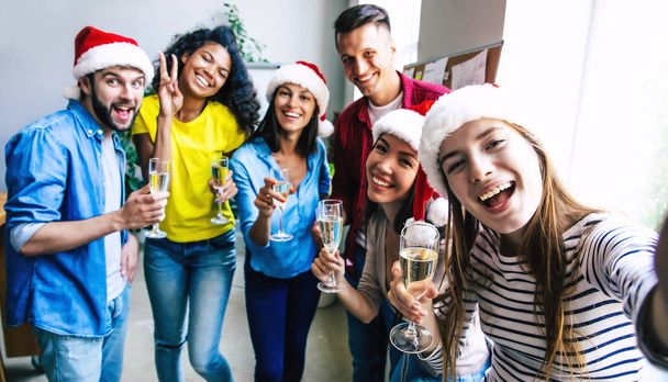 Ομάδα από χαρούμενους πολυφυλικούς φίλους που γιορτάζουν μαζί τα Χριστούγεννα με ποτήρια σαμπάνιας - Φωτογραφία, εικόνα