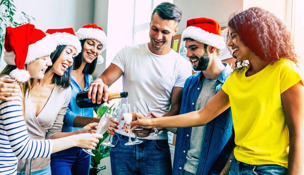 Група щасливих багаторасових друзів святкують разом Різдво і поливають шампанське в окулярах
 - Фото, зображення