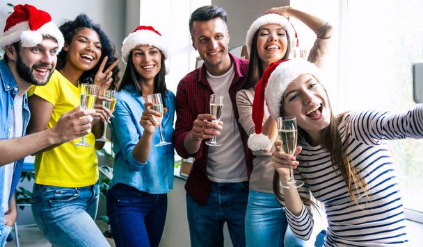 Group of happy friends celebrating together Christmas and posing for selfie with glasses of champagne - Foto, immagini