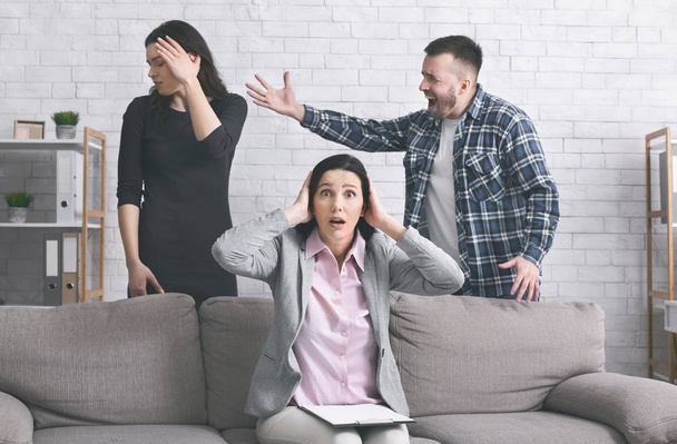 Σοκαρισμένος οικογενειακός σύμβουλος ακούγοντας εξαγριωμένοι συζύγους να μαλώνουν στο γραφείο της - Φωτογραφία, εικόνα