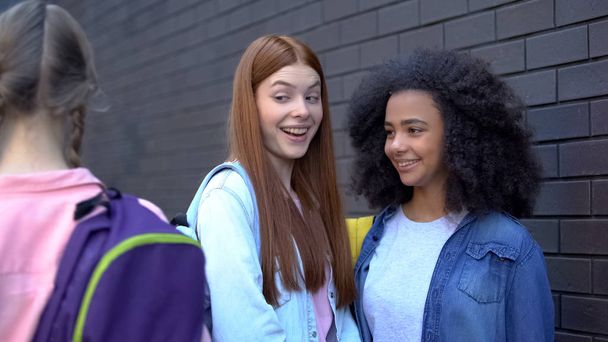 Female teenagers laughing at new student passing by, school rejection, offend - Foto, Bild