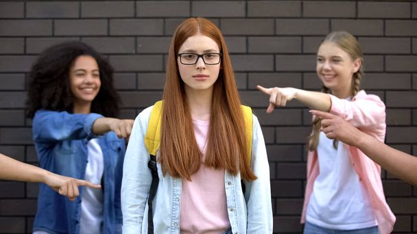 Depressed bullying victim eyeglasses looking camera, teenagers pointing fingers - Foto, imagen