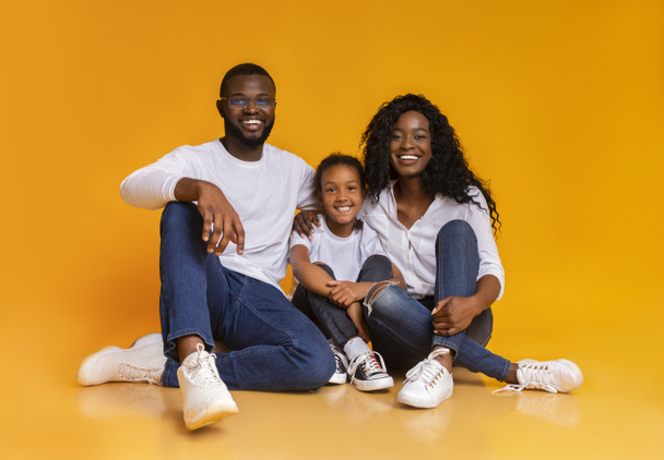 Retrato de familia negra feliz sonriendo sobre fondo amarillo del estudio
 - Foto, Imagen