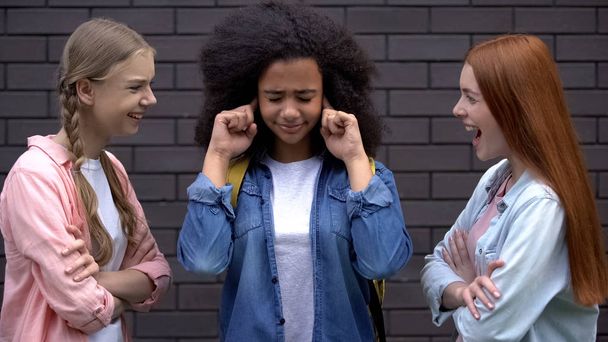 Молоді жінки глузують з чорного однокласника, знущання жертви закривають вуха, конфлікт
 - Фото, зображення