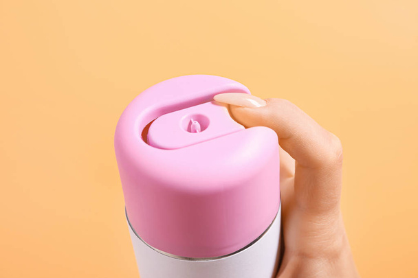 Θηλυκό χέρι με ένα μπουκάλι αποσμητικό αέρα στο φόντο χρώμα, κοντινό πλάνο - Φωτογραφία, εικόνα
