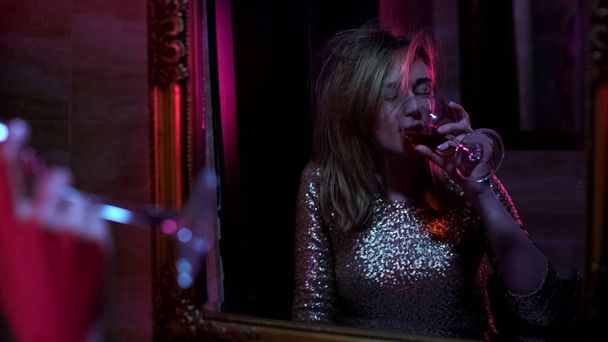 Intoxicated woman drinking wine in front of mirror, night club party, lifestyle - Фото, зображення
