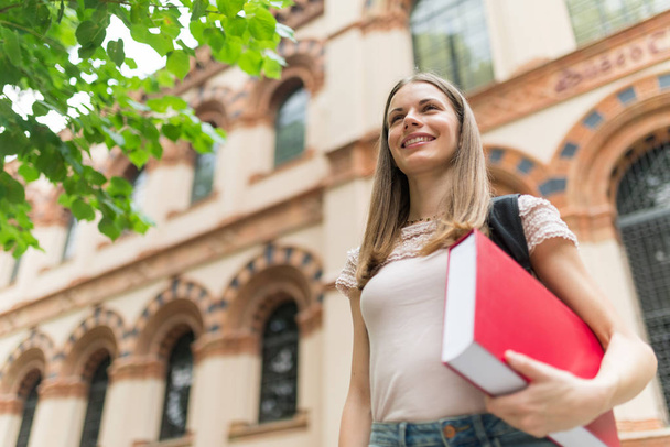 Portrait of a smiling student in front of her university - Photo, image