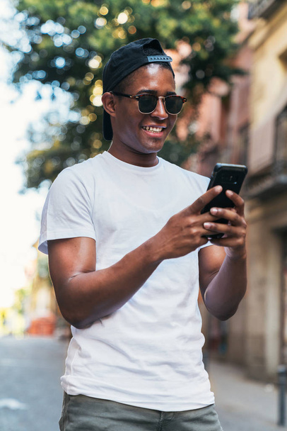 Black man in sunglasses looking at smartphone - Foto, Imagem