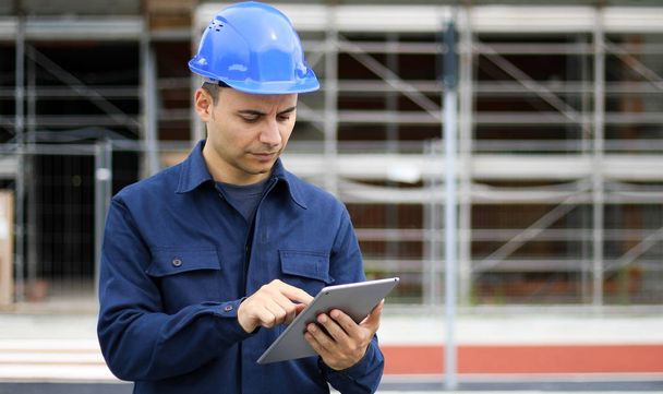 Young engineer man in suit and helmet working on tablet pc - Photo, Image