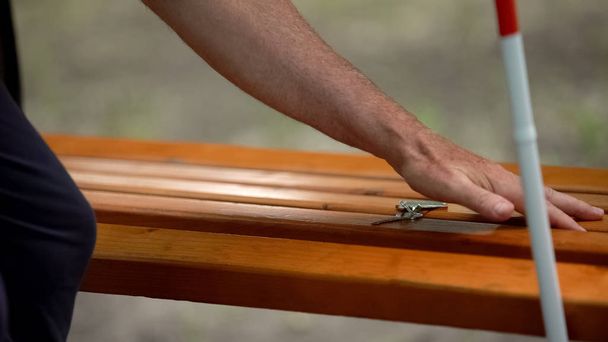 Blind finding lost keys on bench, visual challenges in everyday life of impaired - Fotó, kép