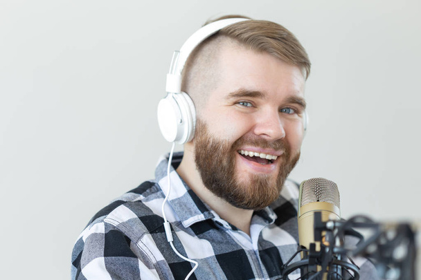 Radio and DJ concept - Man with microphone and big headphone is smiling - Φωτογραφία, εικόνα