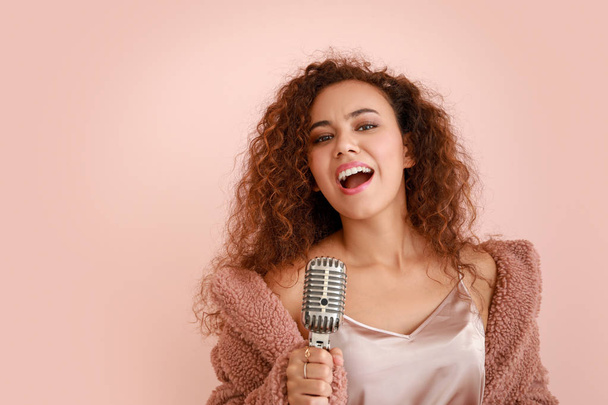 Beautiful African-American female singer with microphone on color background - Фото, изображение