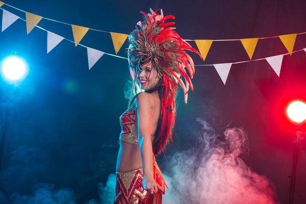 Карнавал, танцовщица и праздничная концепция - брюнетка в костюме кабаре и головном уборе с натуральными перьями и стразами
. - Фото, изображение
