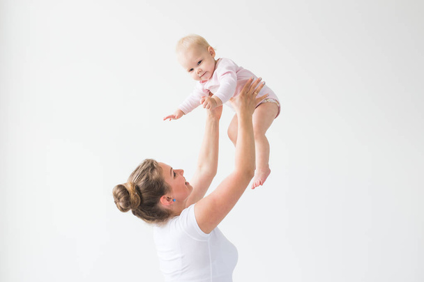 Mother lifting baby girl. Happy mother picks up and throws his lifting a small child. Home atmosphere, happy family laughing baby - Photo, Image