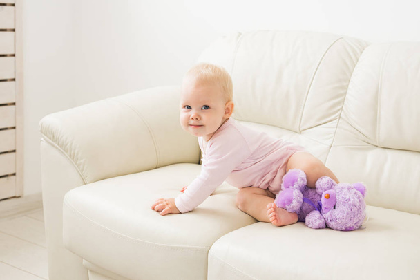 Child, childhood and kids concept - Portrait of charming baby girl near the couch - Photo, Image