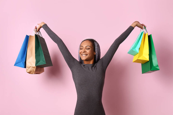 glücklich afrikanisch-amerikanische Frau mit Einkaufstaschen auf farbigem Hintergrund - Foto, Bild