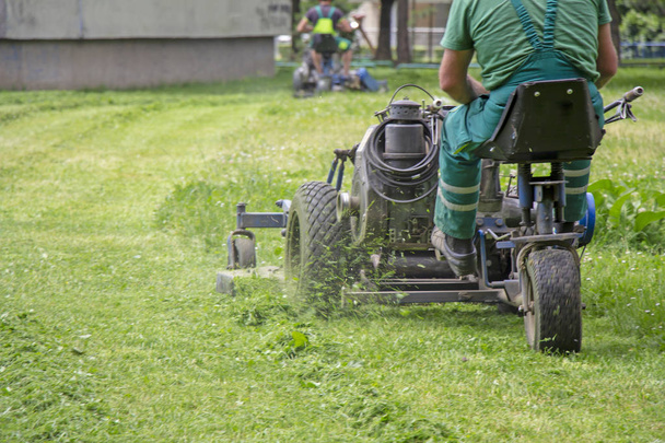 Worker mowing grass in a city park - Fotó, kép