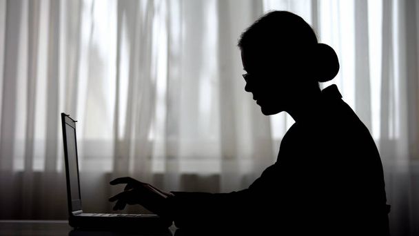 Silhouette of businesswoman working on laptop in early morning, meeting deadline - Fotografie, Obrázek