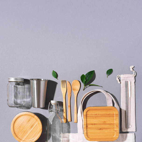 Sustainable lifestyle. Zero waste, plastic free shopping concept. Cotton bags, glass jar, bottle, metal cup, straws for drinking, bamboo cutlery and boxes on gray background. - Photo, image