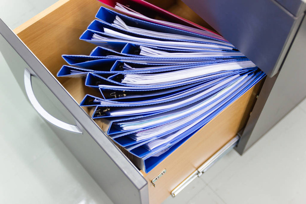 Документы голубой папки в шкафу хранения файлов
  - Фото, изображение