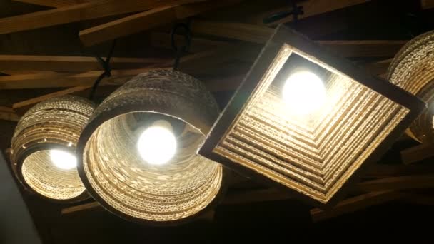 Brown wicker chandeliers, with bright luminous lamps, glow on the ceiling, swaying slightly. Close-up. - Footage, Video