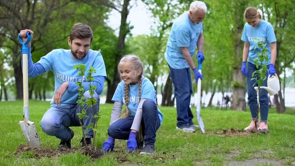 Happy volunteers family planting tree saplings outdoors, enjoying made work - Fotoğraf, Görsel