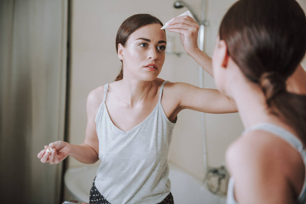 Ayna önünde yüz jeli uygulayan ciddi güzel kadın - Fotoğraf, Görsel