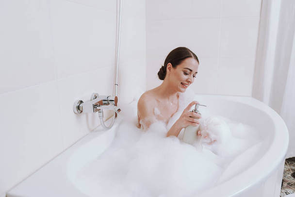 Happy young woman applying shower gel in the bathroom - Valokuva, kuva