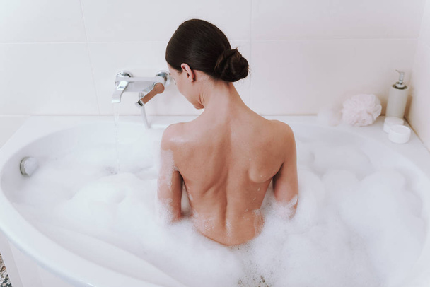 Rear view of a nude woman taking shower - Foto, afbeelding