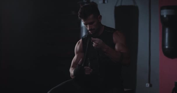 Attractive guy wraps his hands with a professional bandages before training in a cross fitness class - Materiał filmowy, wideo
