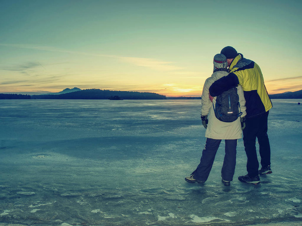 Οι εραστές κρατούν ο ένας τον άλλον στον πάγο στην παγωμένη λιμνοθάλασσα και βλέπουν τον ήλιο - Φωτογραφία, εικόνα