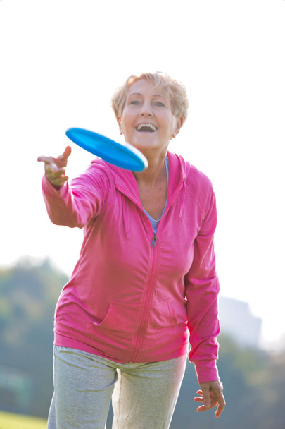 Uśmiechający się i zdrowy senior kobieta rzucając płyty w parku - Zdjęcie, obraz