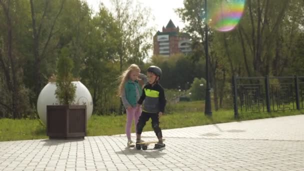 A preschooler boy in a protective helmet rides in the park. Summer - Felvétel, videó