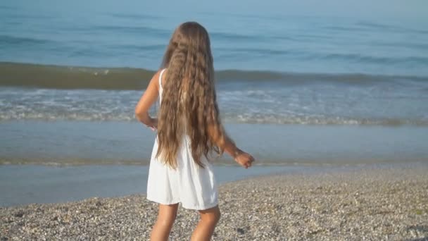 白いドレスを着た小さな女の子が海の近くを歩く - 映像、動画
