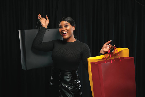 Young woman in dress shopping on black background - Valokuva, kuva