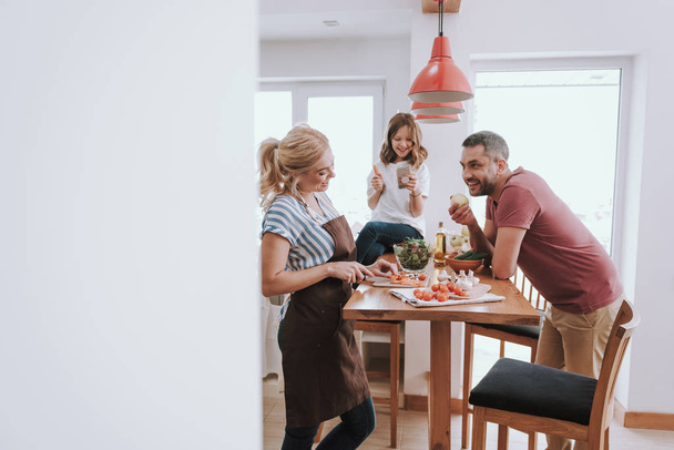 Happy family spending time together in kitchen while preparing for dinner - Фото, изображение