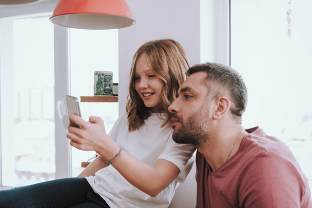 Adorable little girl and her father watching funny videos on smartphone - Zdjęcie, obraz