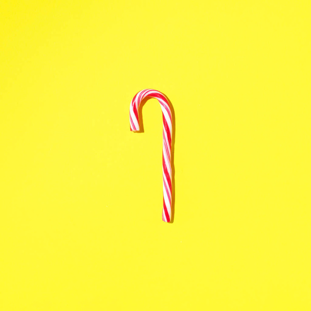 Christmas candy cane on yellow background with copy space. Top view. Greeting card on Christmas and New Year. Minimal festive concept - Valokuva, kuva