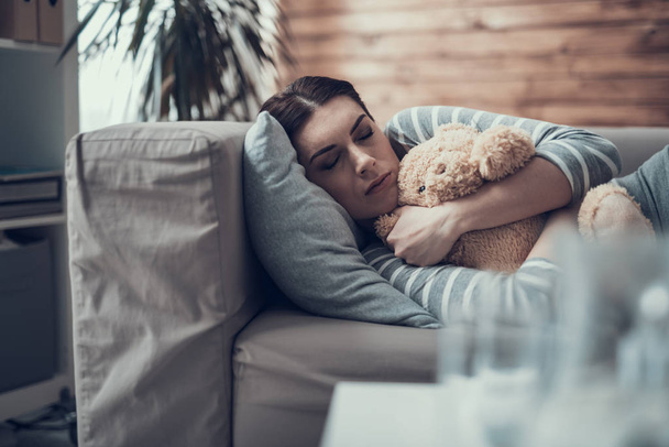 Brunette Caucasian sleepy woman lying on sofa with toy in arms - Foto, immagini