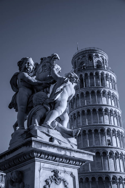 El putti en frente de la torre inclinada de Pisa al atardecer
 - Foto, imagen