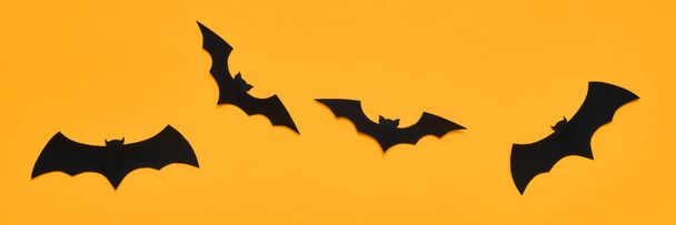 Halloween and decoration concept. Black paper bats flying over orange background. Halloween banner. - Fotografie, Obrázek