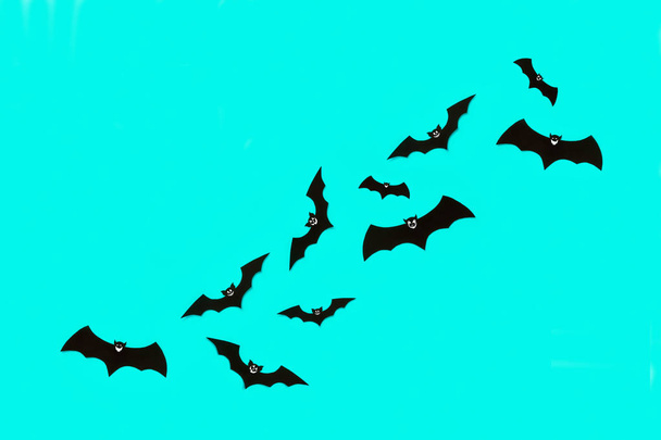 Halloween and decoration concept. Cute smiling black paper bats flying over pastel blue background. Halloween background. - Fotografie, Obrázek