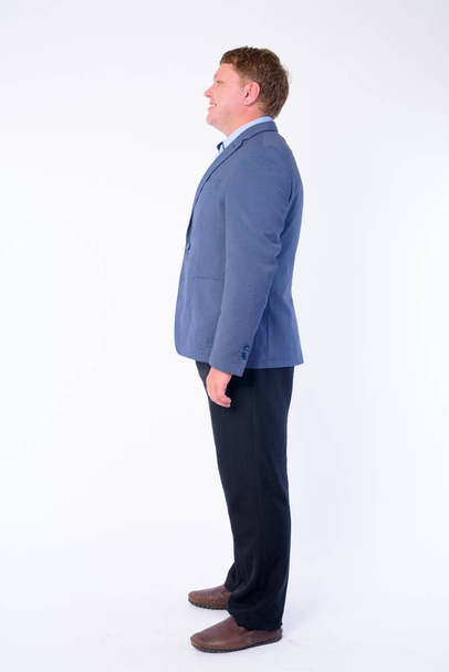 Full body shot profile view of happy overweight businessman in suit smiling - Photo, image