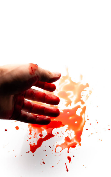 Mão ensanguentada masculina sobre um fundo branco com salpicos e gotas de sangue
. - Foto, Imagem