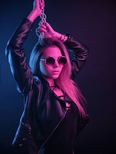beautiful stylish fashionable girl in bodysuit posing in photo Studio on dark background with chains in neon light - Foto, imagen