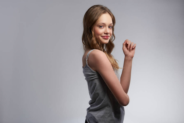 Charming teen girl standing against gray-white background - Foto, Imagen