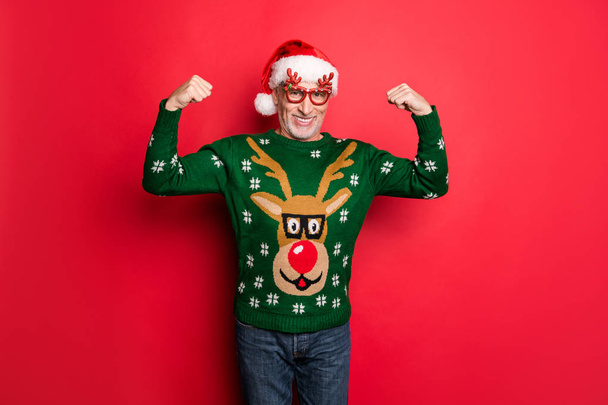Merry december x-mas newyear. Photo of white grey-haired handsome funky feeling young guy demonstrating his huge triceps on hands wear green jeans retro jumper isolated bright color background - Photo, image