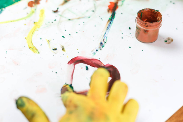 manos amarillas en pinturas sobre mesa ligera pintadas en diferentes colores
 - Foto, Imagen