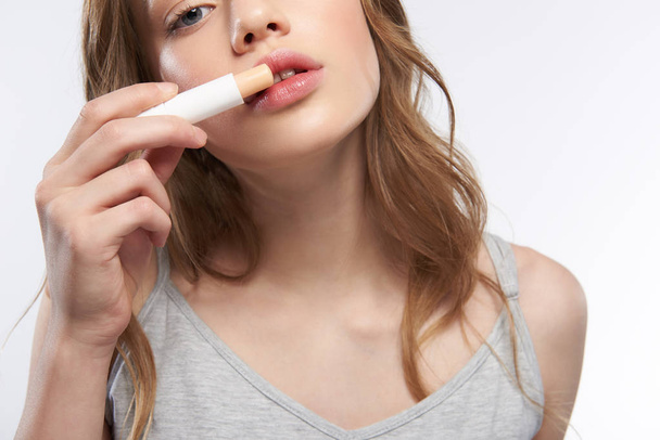 Charming teen girl with beautiful full lips using hygienic lipstick - Fotó, kép