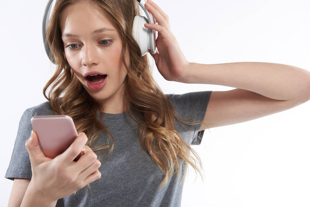 Charming teen girl in wireless headphones using cellphone - Foto, Bild